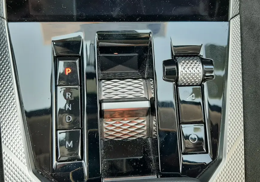 Gros plan sur la console centrale noire brillante du DS4 2024 avec sélecteur de boîte auto et molette texturée.