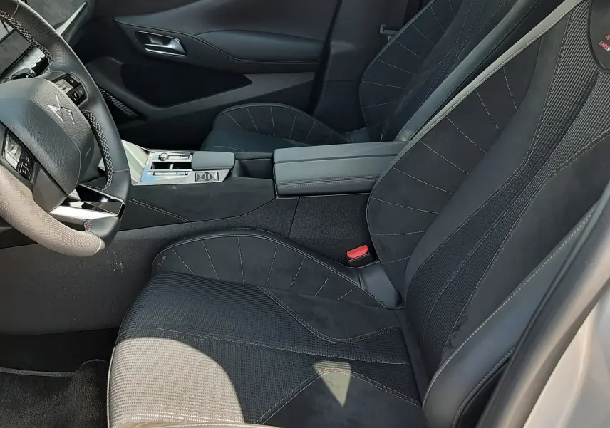 Vue intérieure côté conducteur du DS4 2024 en Cristal Pearl, sièges noirs en cuir et alcantara avec surpiqûres rouges.