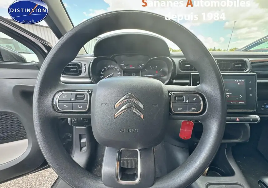 Vue centrée sur le volant de la Citroën C3 noire 2023 avec commandes audio et tableau de bord numérique visible.