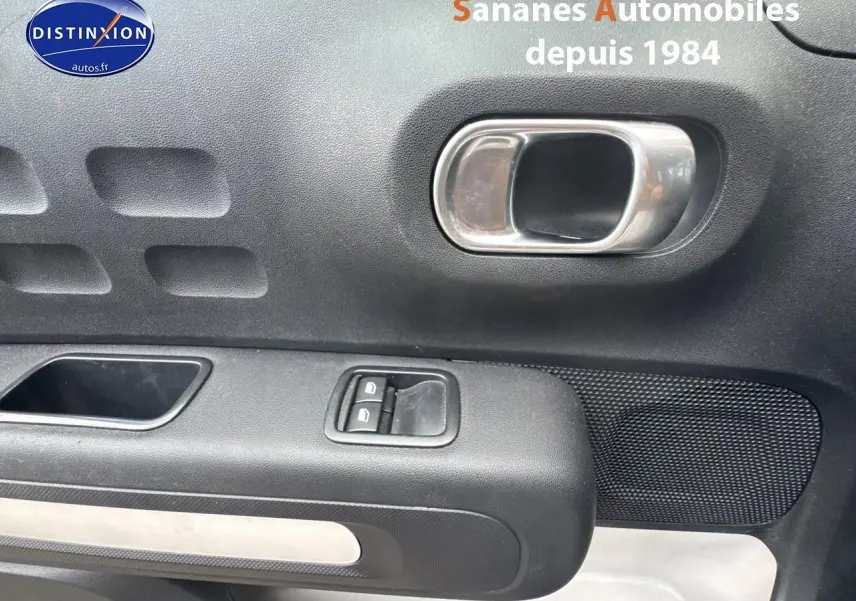 Poignée intérieure et commandes des lève-vitres côté gauche d'une Citroën C3 noire version 1.5 BlueHDi 2023.