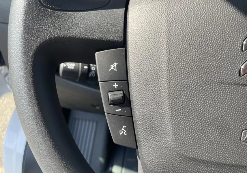 Gros plan sur les commandes de volume et de coupure du son au volant du Citroën Jumper blanc 2023.