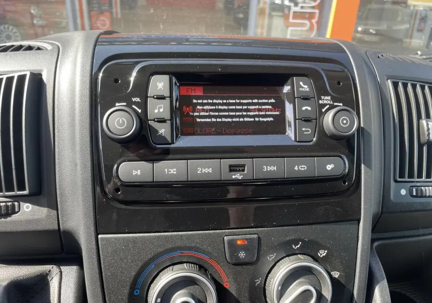 Tableau de bord noir du Citroën Jumper 2023 avec système audio, commandes climatisation et port USB visible.