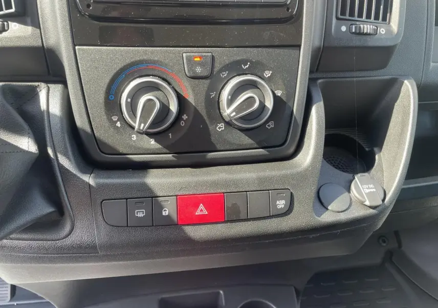 Gros plan sur la console centrale du Citroën Jumper 2023, montrant les commandes de climatisation et boutons de sécurité.