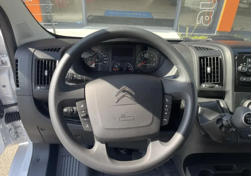 Vue rapprochée du volant et du tableau de bord du Citroën Jumper blanc 2023 avec boîte manuelle et commandes au volant.