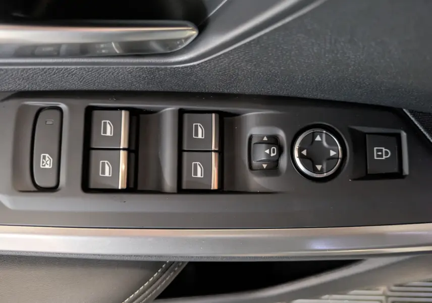 Vue rapprochée des commandes de lève-vitres et réglage des rétroviseurs côté conducteur du Peugeot 3008 blanc Okenite.