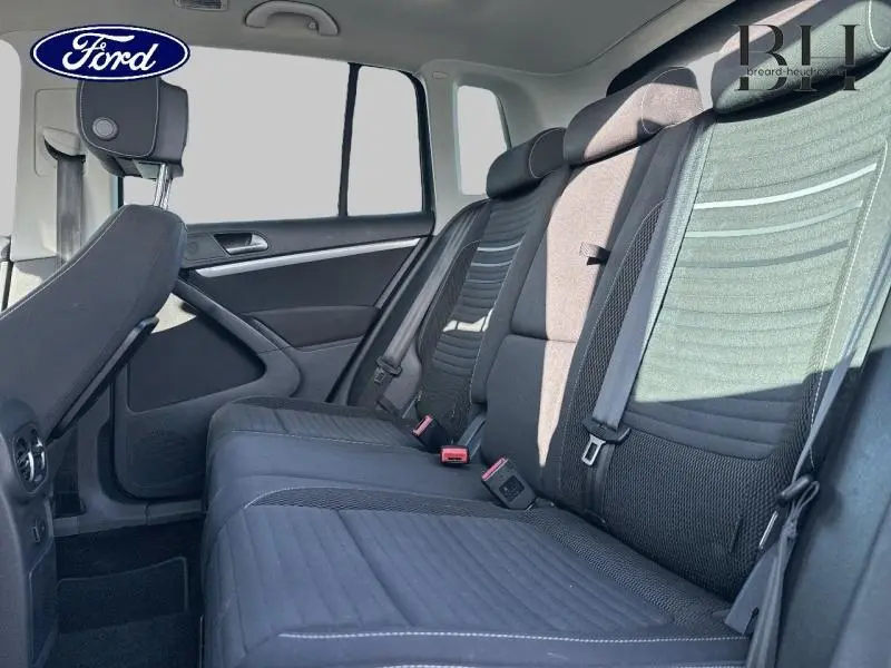 Vue intérieure de la banquette arrière noire du Volkswagen Tiguan 2016, avec ceintures de sécurité visibles côté droit.