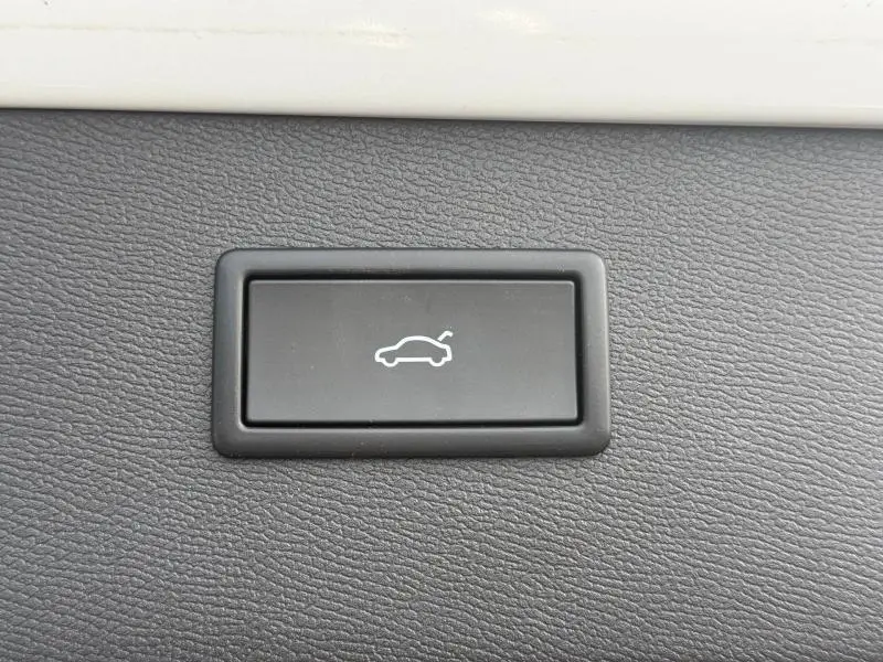 Bouton noir de déverrouillage du coffre sur tableau de bord texturé d'une CUPRA Formentor blanc Nevada métallisé.