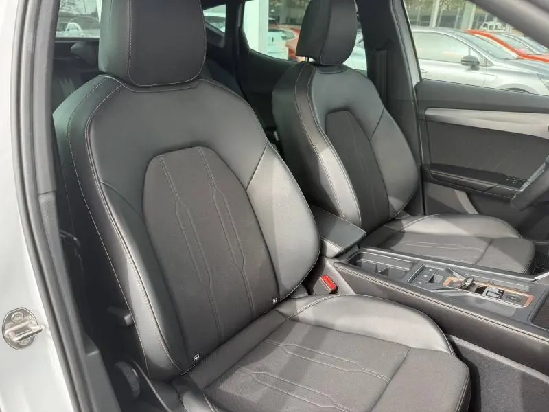 Vue intérieure des sièges avant en cuir noir du CUPRA Formentor blanc Nevada métallisé, avec console centrale visible côté droit.