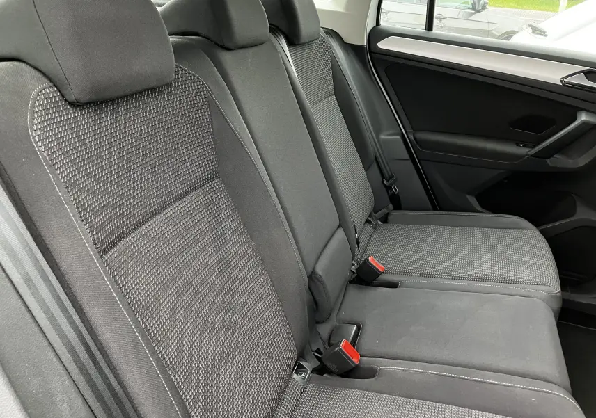 Vue latérale des sièges arrière noirs en tissu du Volkswagen Tiguan blanc 2018, soulignant les ceintures de sécurité et appuie-têtes.