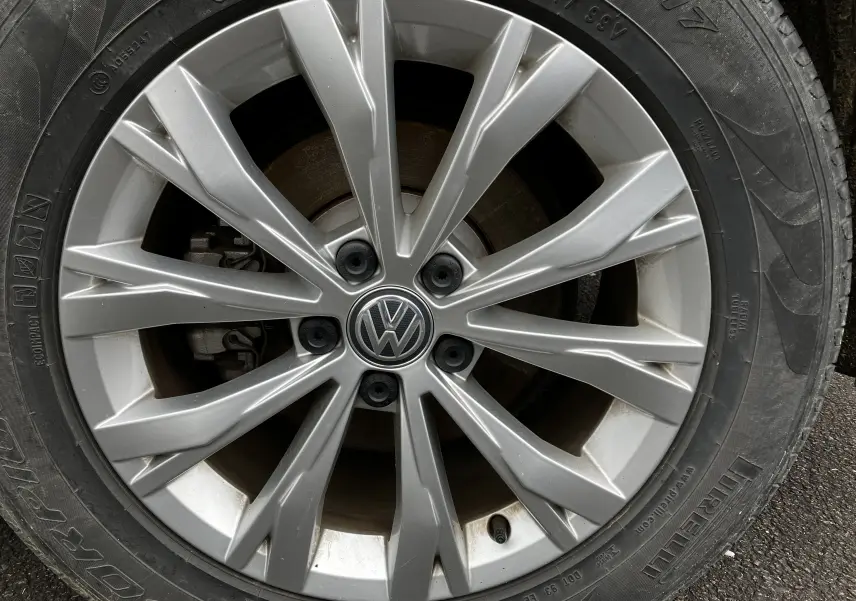 Gros plan sur la jante aluminium argentée du Volkswagen Tiguan blanc, mettant en valeur le logo VW central.