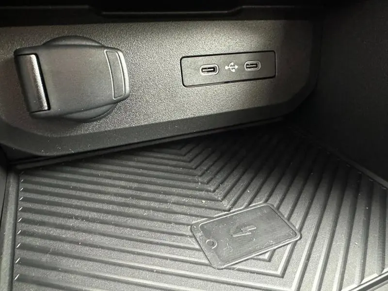 Gros plan sur la console centrale noire du Dacia Duster 2025, montrant deux ports USB-C et une prise 12V.