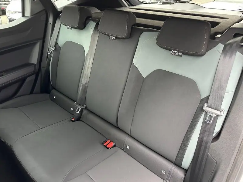 Vue intérieure de la banquette arrière bicolore noire et grise du Dacia Duster 2025, avec appuie-têtes et ceintures visibles.