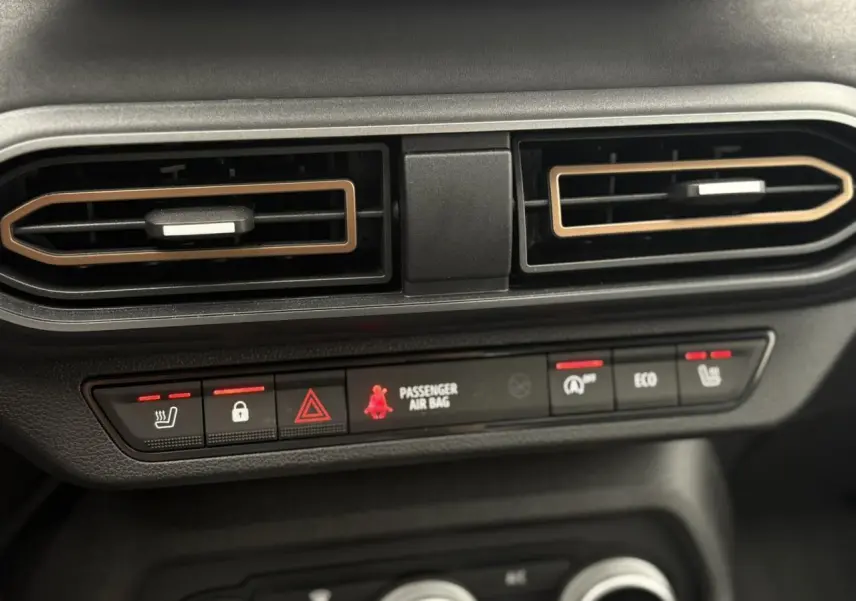 Gros plan sur les aérateurs et les commandes chauffantes du tableau de bord de la Dacia Sandero Stepway gris schiste.