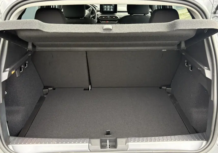 Coffre ouvert de la Dacia Sandero Stepway gris schiste, montrant l'espace de chargement et la banquette arrière rabattable.