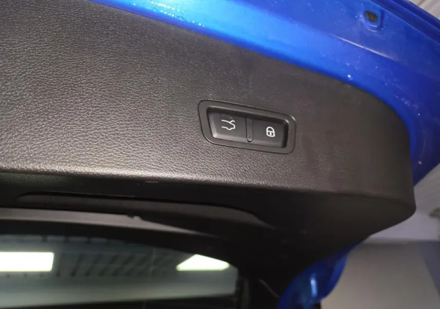 Bouton d'ouverture et de verrouillage du hayon sur la partie intérieure du coffre bleu d'une Alfa Romeo Tonale 2024.