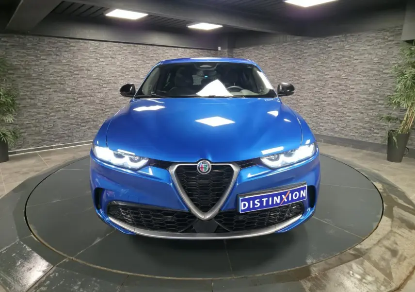 Vue frontale d'une Alfa Romeo Tonale 2024 bleu métallisé avec calandre caractéristique et phares LED allumés.