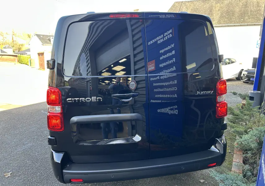 Vue arrière d'un Citroën Jumpy cabine approfondie noir, avec portes arrière vitrées et feux rouges allumés.