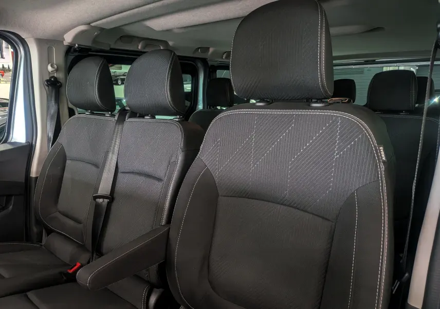 Vue intérieure rapprochée des sièges avant en tissu noir du Nissan Primastar Combi gris Highland, version 2026.
