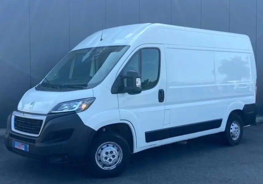 Vue 3/4 avant droit d'un Peugeot Boxer Fourgon blanc de 2019 avec pare-chocs noirs et porte latérale coulissante.