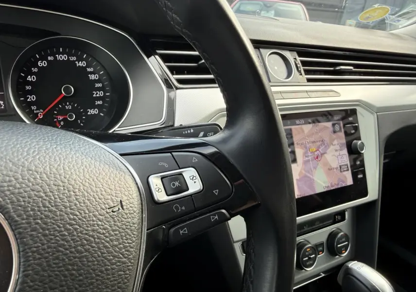 Intérieur de Volkswagen Passat 2018 vu côté conducteur, volant cuir et écran de navigation affichant une carte.