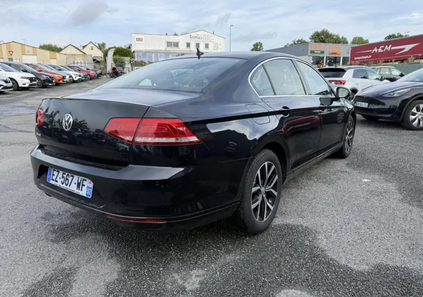 Volkswagen Passat noire vue 3/4 arrière droit, feux arrière LED et jantes alliage 16 pouces visibles.