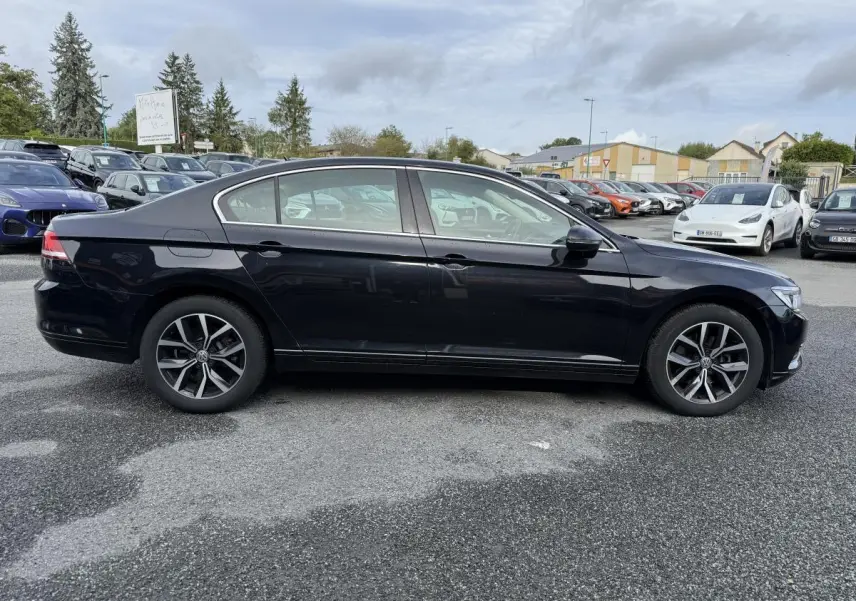 Profil côté gauche d'une Volkswagen Passat noire 2018 avec jantes alliage et vitres teintées sur parking.