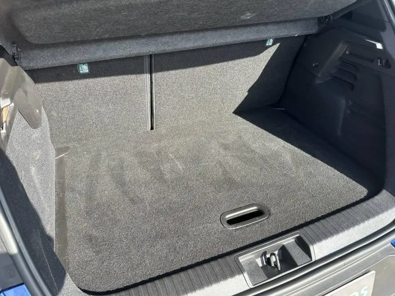Coffre ouvert vu de l'arrière d'un Renault Captur 2025 Bleu Iron/Noir Étoilé, montrant un espace de rangement propre et spacieux.