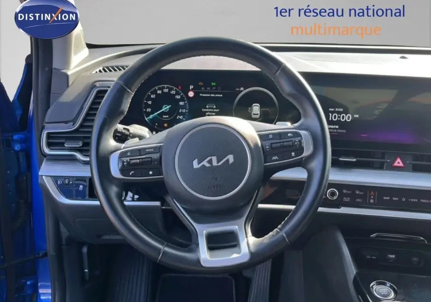 Vue intérieure centrée sur le volant cuir noir du Kia Sportage 2022, avec tableau de bord digital et écran tactile.