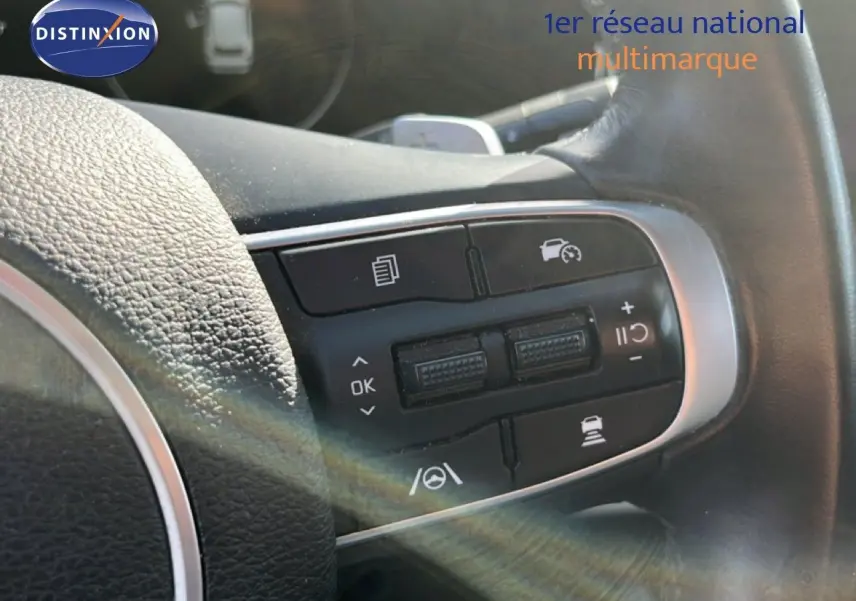 Gros plan sur les commandes au volant en cuir noir du Kia Sportage 2022, version bleu fusion métal.