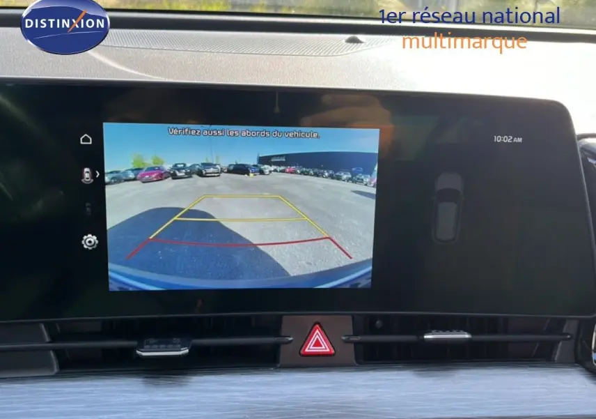 Écran central du Kia Sportage 2022 bleu fusion, affichant la caméra de recul avec lignes de guidage colorées.