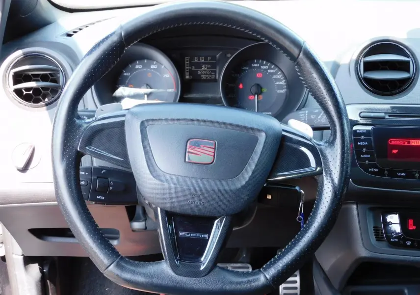 Volant cuir perforé avec logo SEAT et inscription CUPRA, tableau de bord et console centrale d'une Ibiza noire vue de face.
