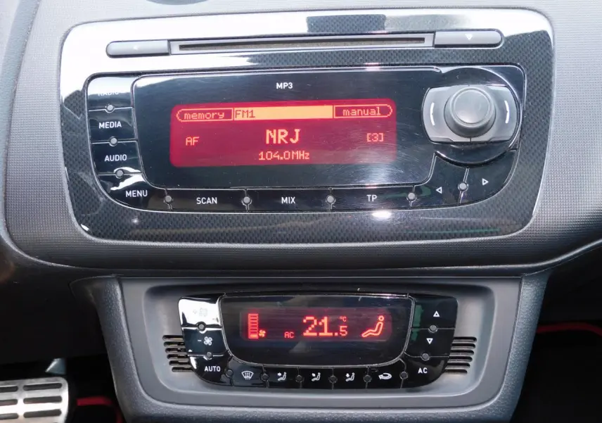 Tableau de bord de la SEAT Ibiza Cupra 2011 noir, affichage radio NRJ et climatisation automatique à 21,5°C.