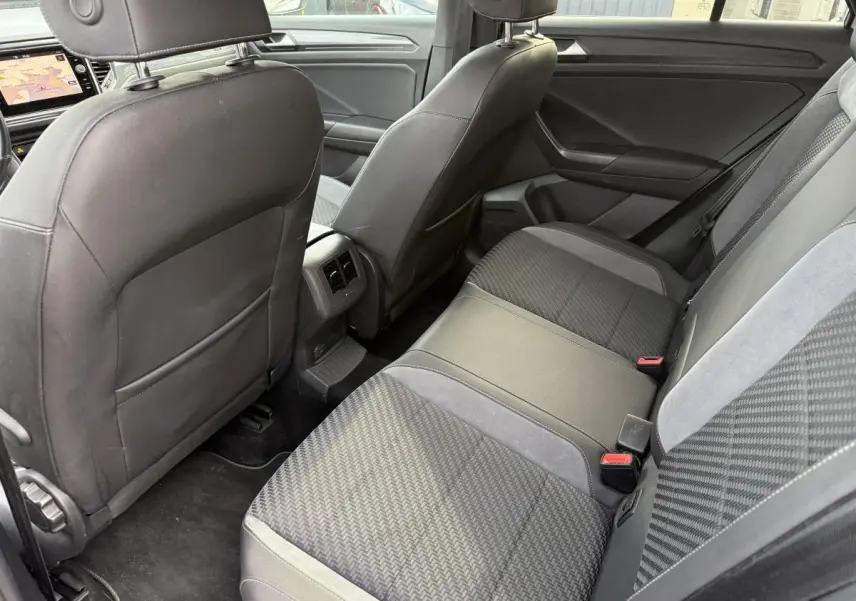 Vue intérieure arrière du Volkswagen T-Roc 1.5 TSI R-Line avec sièges en tissu gris et accoudoirs en simili-cuir noir.