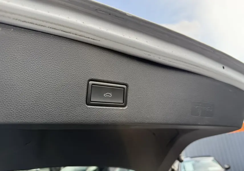 Bouton d'ouverture électrique du hayon sur le coffre d'un Volkswagen T-Roc gris, vue intérieure arrière.