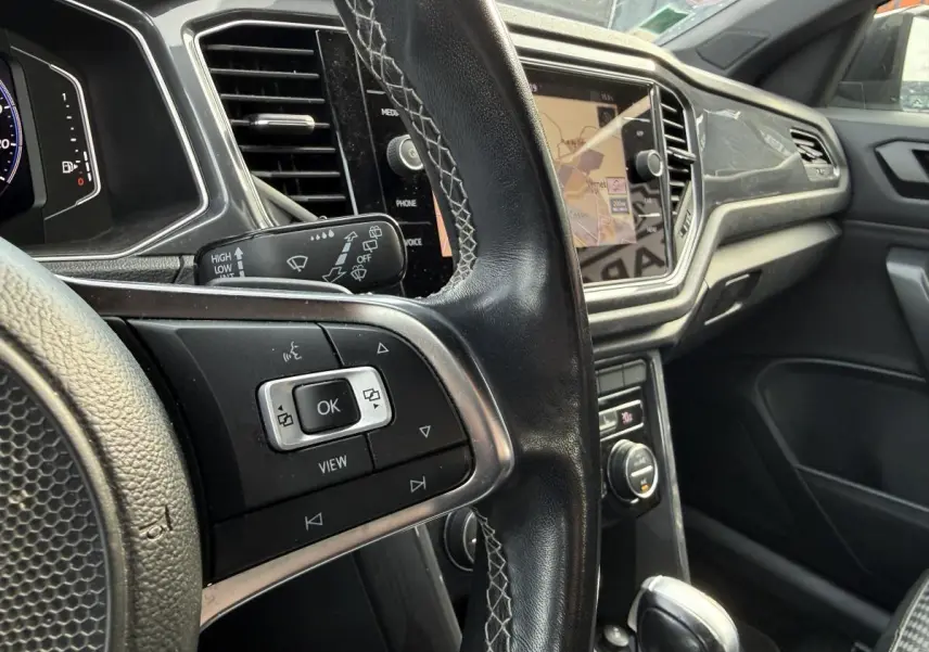 Vue intérieure rapprochée du volant en cuir noir et de la console centrale avec écran tactile du Volkswagen T-Roc R-Line 2020.