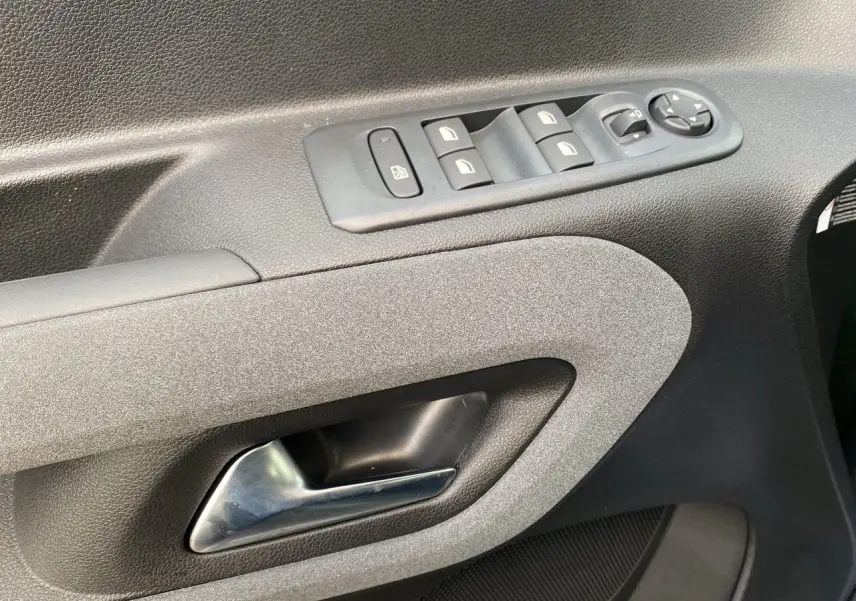 Gros plan sur la poignée intérieure et les commandes des vitres côté conducteur du Peugeot Rifter 2025, finition tissu gris-noir.