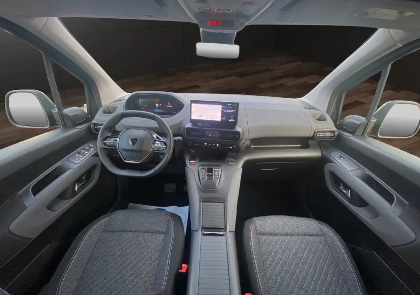 Vue intérieure avant du Peugeot Rifter 2025 avec tableau de bord gris noir et sièges tissu gris foncé.