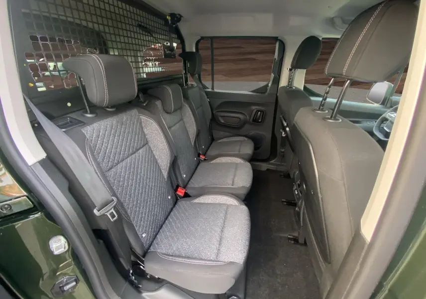 Intérieur du Peugeot Rifter 2025 vert Sirkka, vue latérale sur les sièges arrière gris tissu avec cloison de séparation.