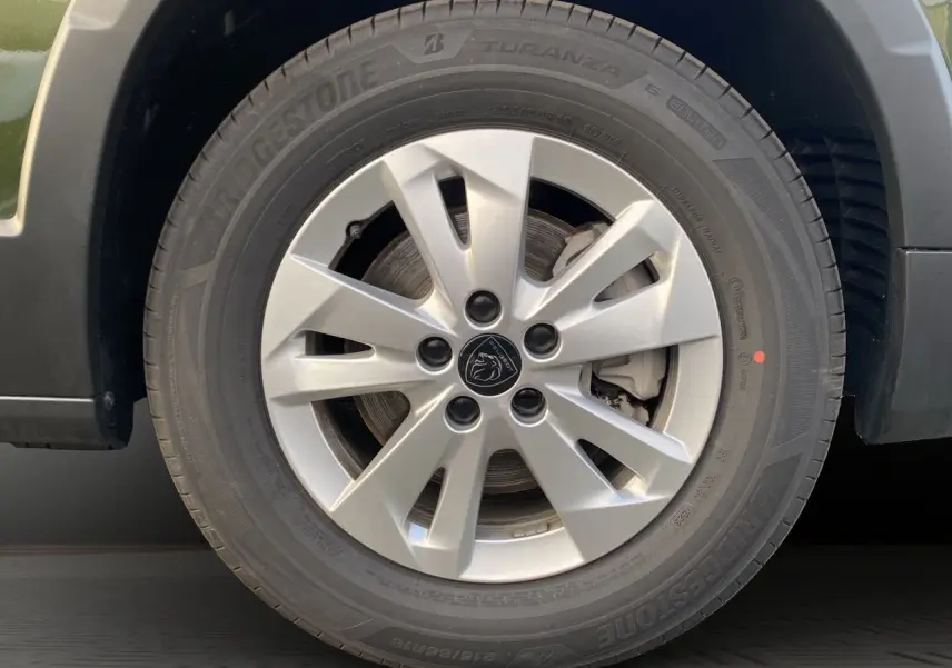 Gros plan sur la jante alliage 16 pouces Taranaki argentée du Peugeot Rifter vert Sirkka, avec logo lion au centre.