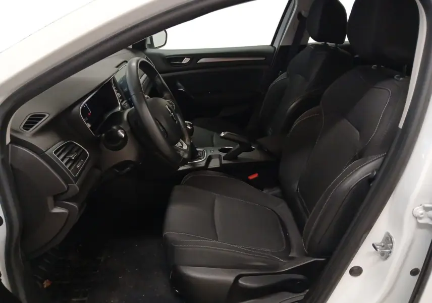 Vue intérieure côté conducteur de la Renault Mégane IV blanche, montrant les sièges noirs et le tableau de bord.