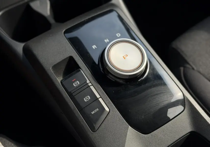 Gros plan sur la console centrale noire du MG3 1.5 Hybrid+ 195 Comfort, avec molette de boîte auto et boutons de contrôle.