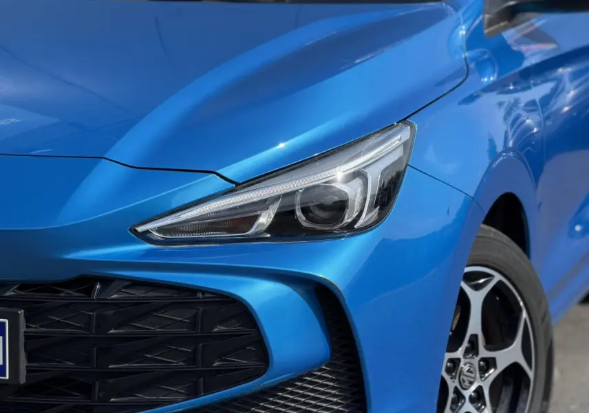 Gros plan sur l’avant droit du MG3 1.5 Hybrid+ 195 Comfort bleu Como, mettant en valeur le phare LED et la calandre noire.