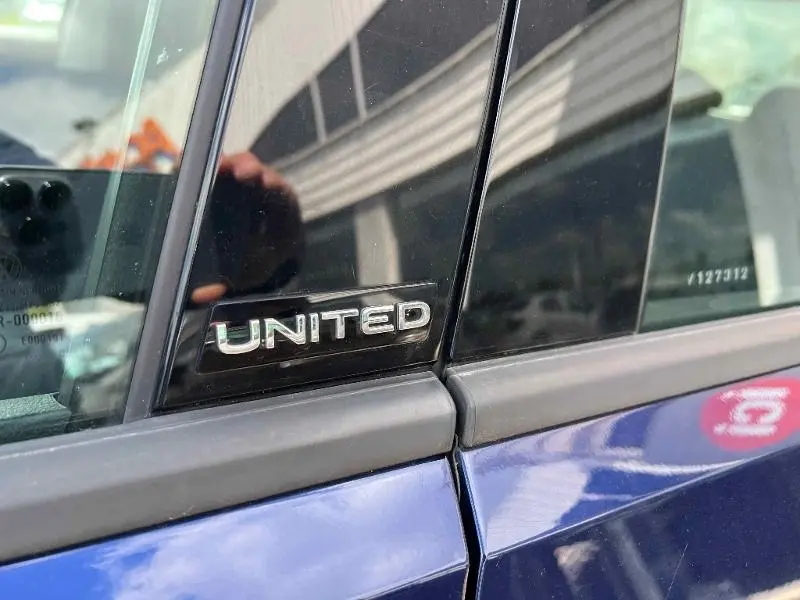 Gros plan sur l'écusson United sur la portière côté gauche d'un Volkswagen T-Roc gris Urano.