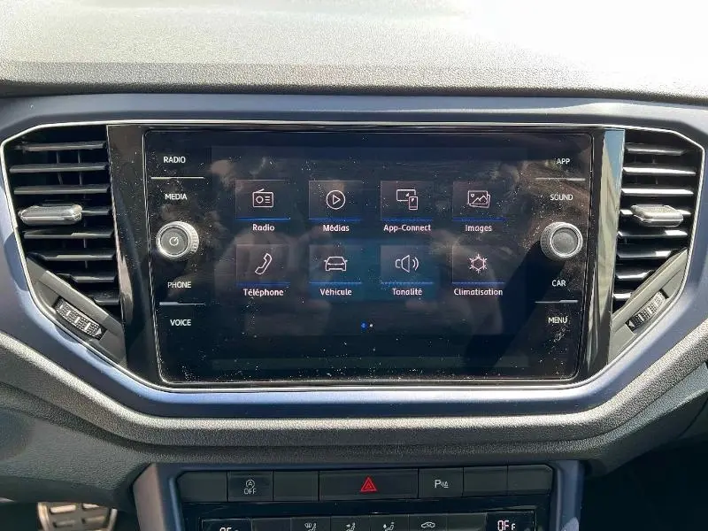 Écran tactile central du Volkswagen T-Roc 1.5 TSI gris, affichant le menu multimédia avec commandes autour.