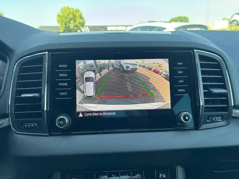 Écran tactile central montrant la caméra de recul d'une Skoda Karoq blanc lune métallisée, vue intérieure avant.