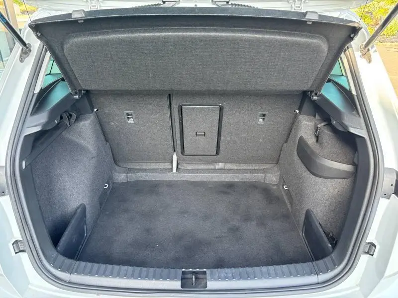 Coffre ouvert du Skoda Karoq blanc Lune métallisé, montrant l'espace de chargement et la trappe à skis centrale.
