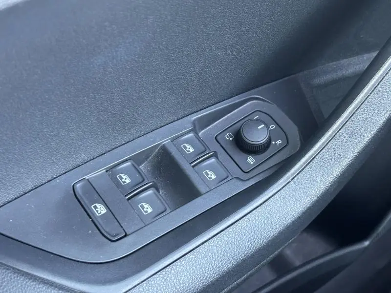 Gros plan sur les commandes des vitres électriques et rétroviseurs côté conducteur d'un Skoda Karoq blanc Lune 2024.