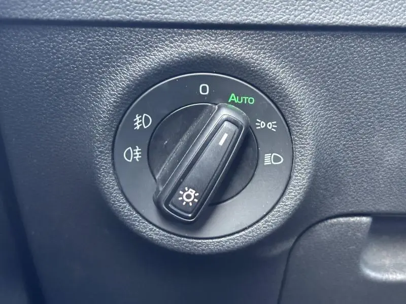 Gros plan sur la molette de réglage des phares du Skoda Karoq blanc Lune métallisé, avec mode automatique activé.