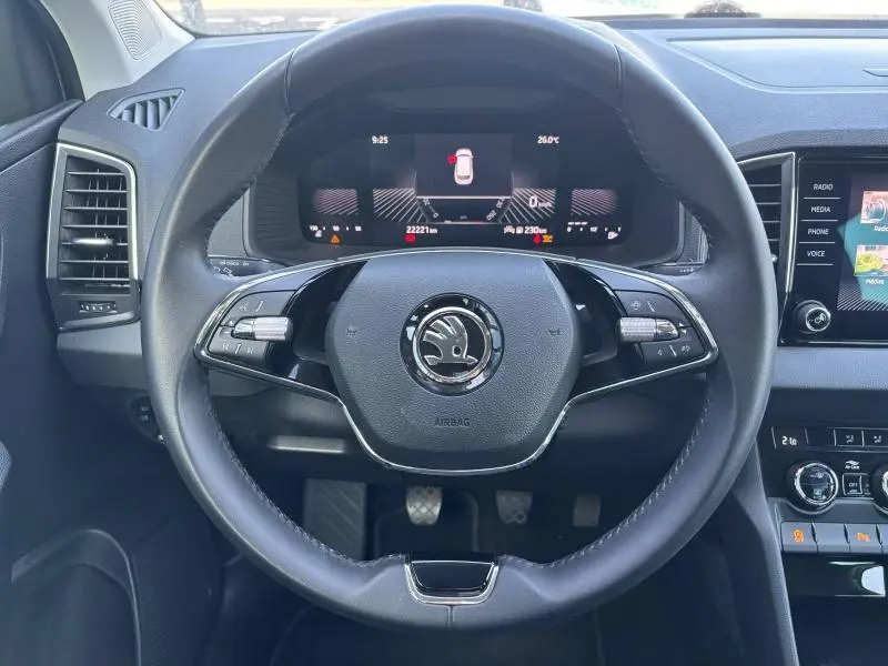 Vue rapprochée du volant cuir multifonction noir du Skoda Karoq 2024 avec tableau de bord numérique et écran tactile latéral.