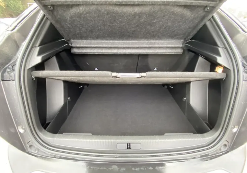 Coffre ouvert vu de l'arrière d'un Peugeot 2008 gris foncé, montrant l'espace de rangement et la tablette cache-bagages.